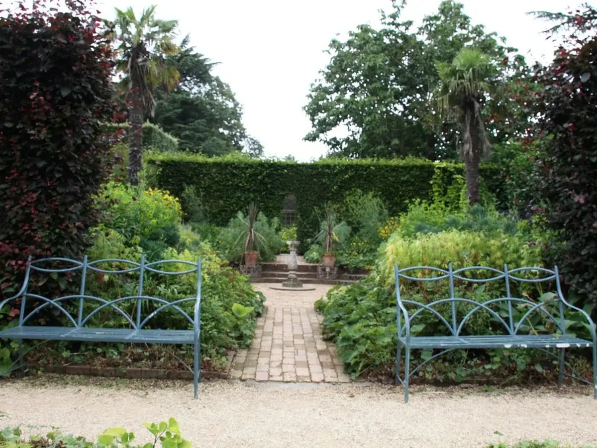 Jardin structuré aux haies taillées et parterres soignés, entretenu par des jardiniers professionnels